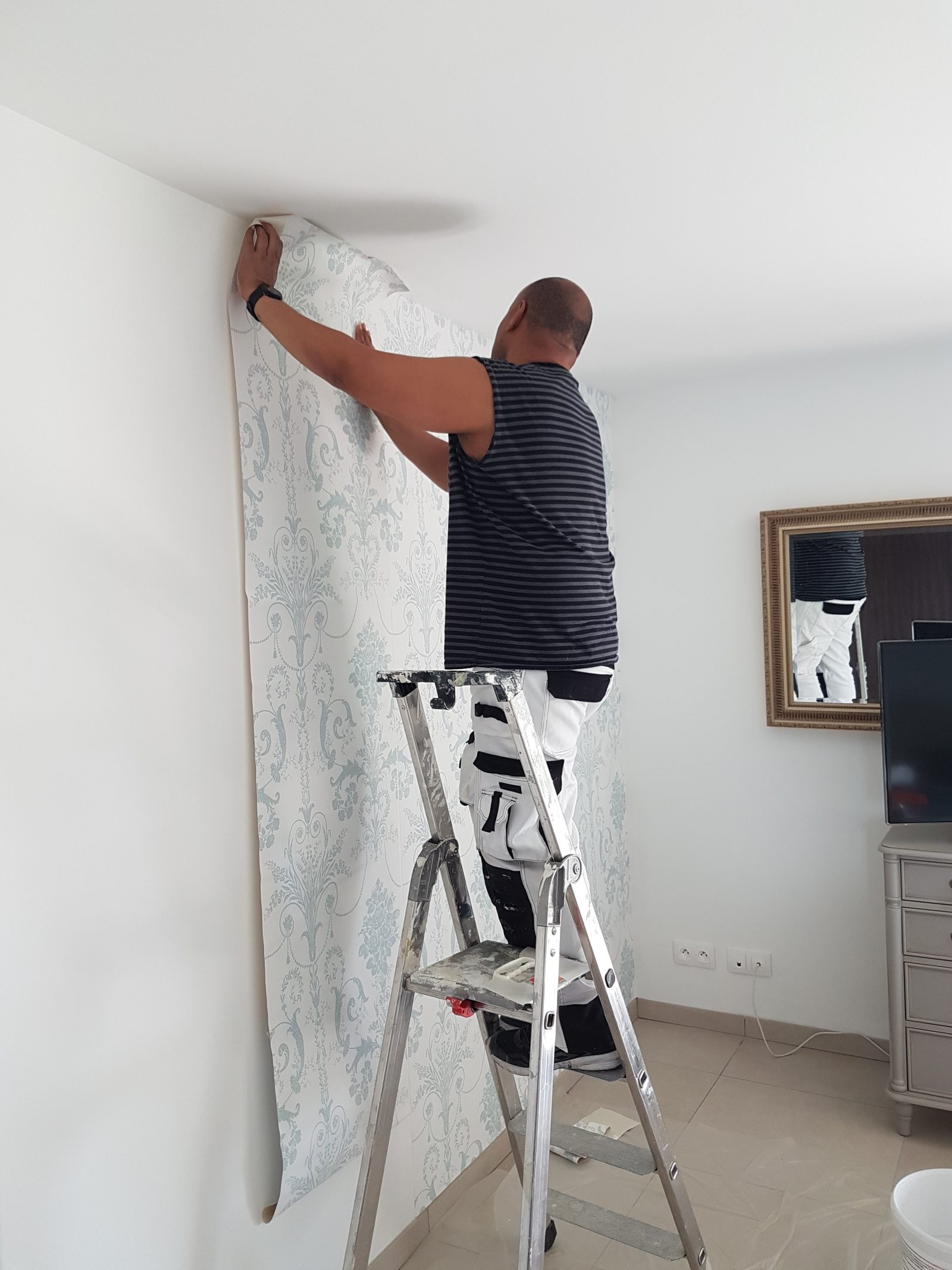 Pose de papier peint à motif en cours sur le mur ACS Déco